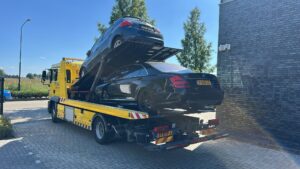 Auto staat met pech en takelt twee personenauto's weg van de straat.