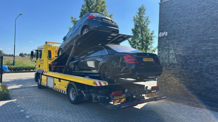 Auto staat met pech en takelt twee personenauto's weg van de straat.